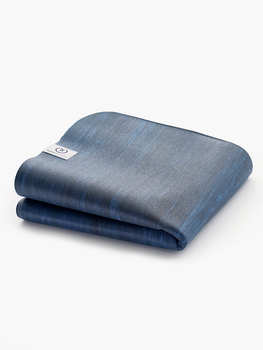 Blue textured non-slip yoga mat rolled up, shot from side angle showing texture and brand tag, fitness and exercise equipment